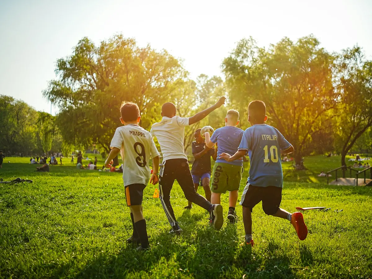 Enfants qui jouent au football dans un parc ensoleillé